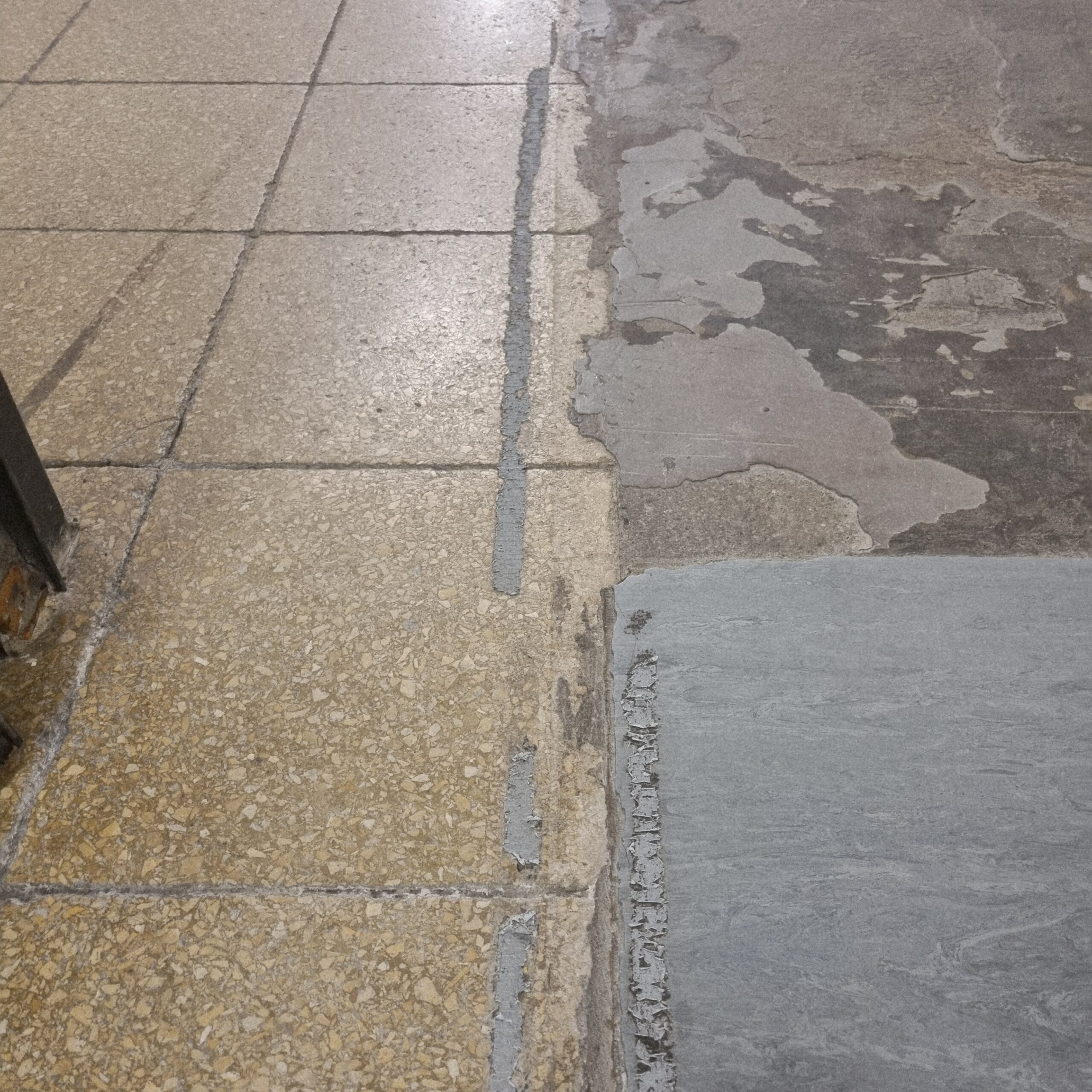 Abgelöste Kleberreste auf Natursteinboden vor der Baureinigung Köln
