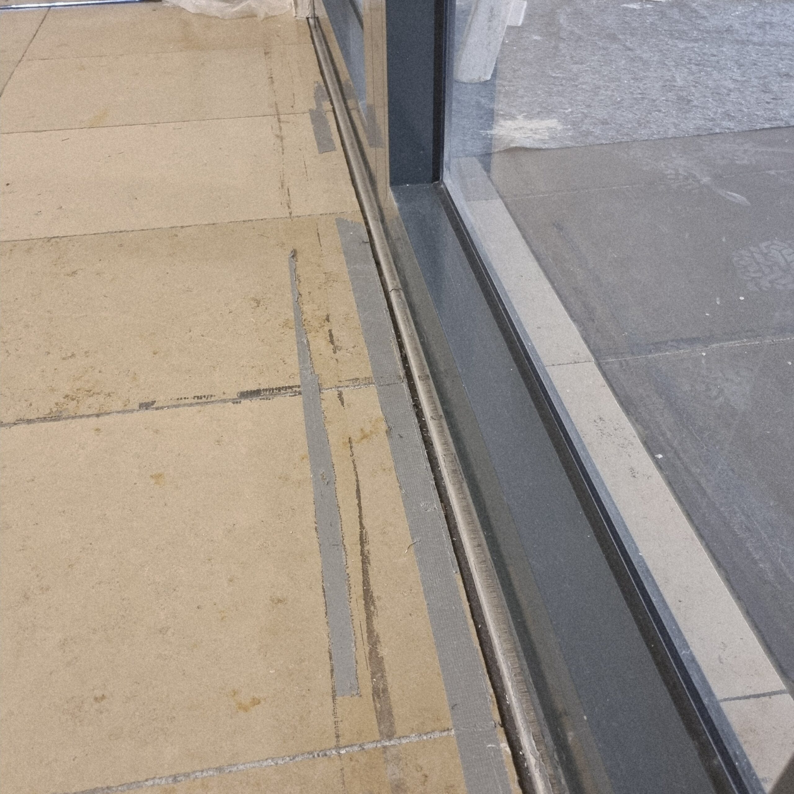 Kleberreste und Panzerbandstreifen an Fensterrahmen – Baureinigung Köln